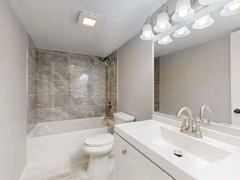 Remodeled bathroom with a tub, vanity, and wall sconce lighting