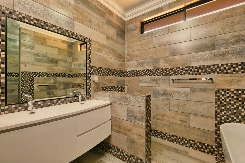Remodeled bathroom with tile walls, a floating vanity, and a large mirror