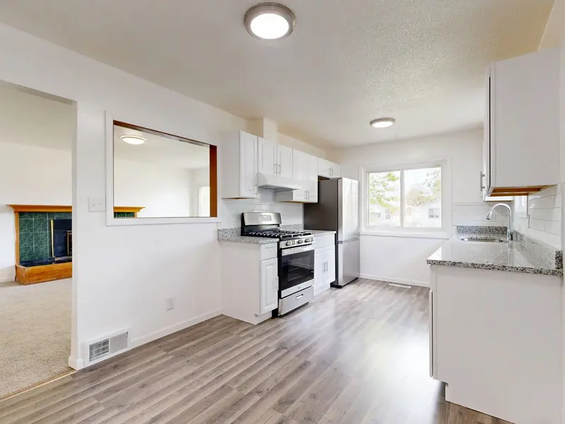 Renovated kitchen with a large island, white cabinetry, and hardwood floors